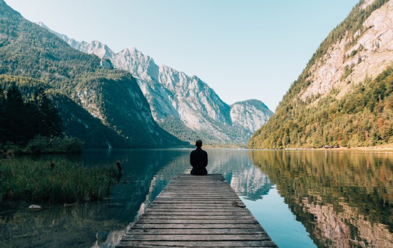 homme médite au bord d'un lac